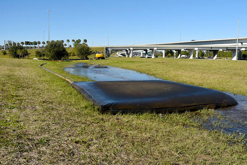 Large black mat on grass with a highway in the background