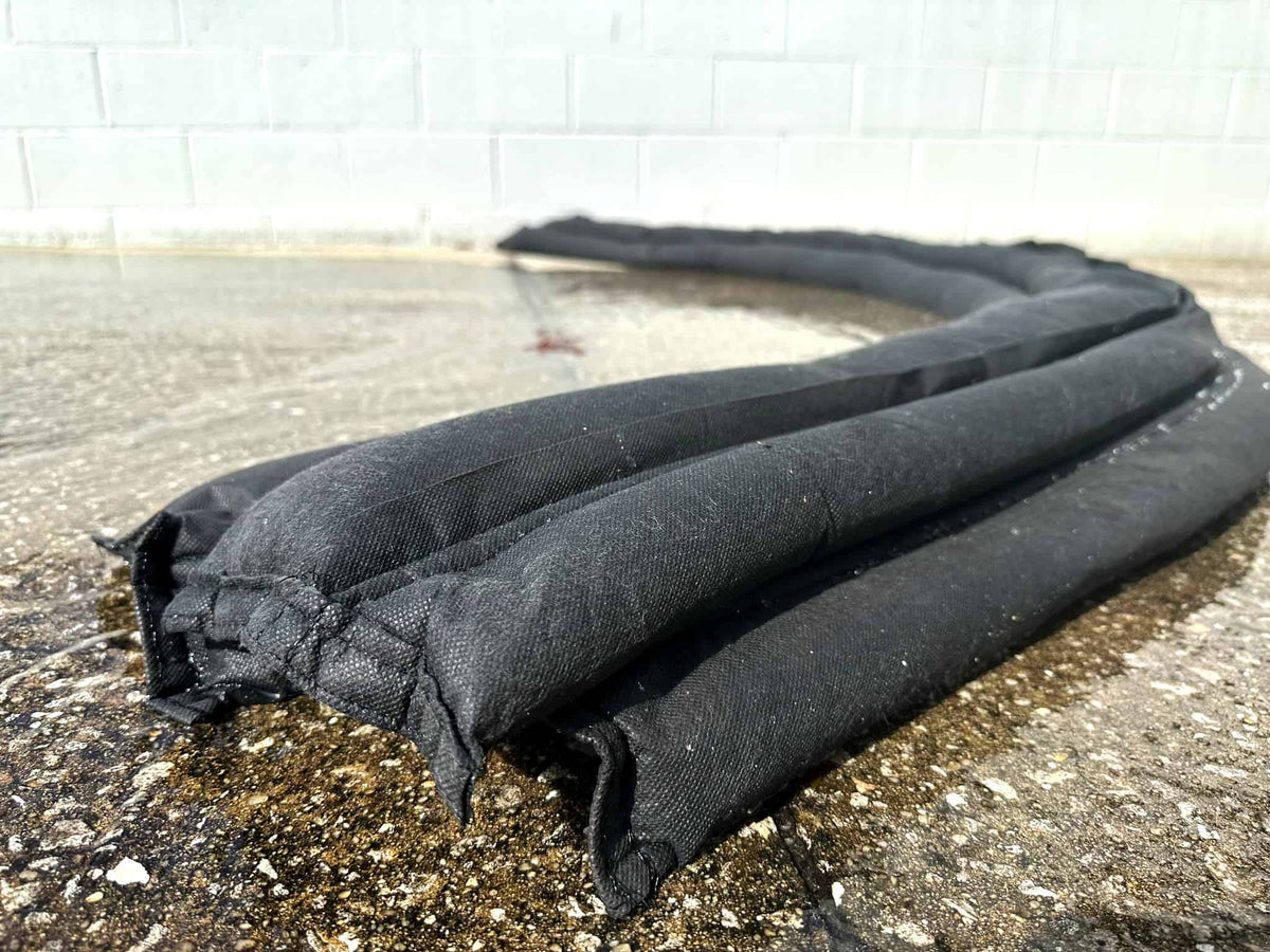 A black sand-less sandbag barrier activated by water, placed against a door to prevent flood waters from entering a property.